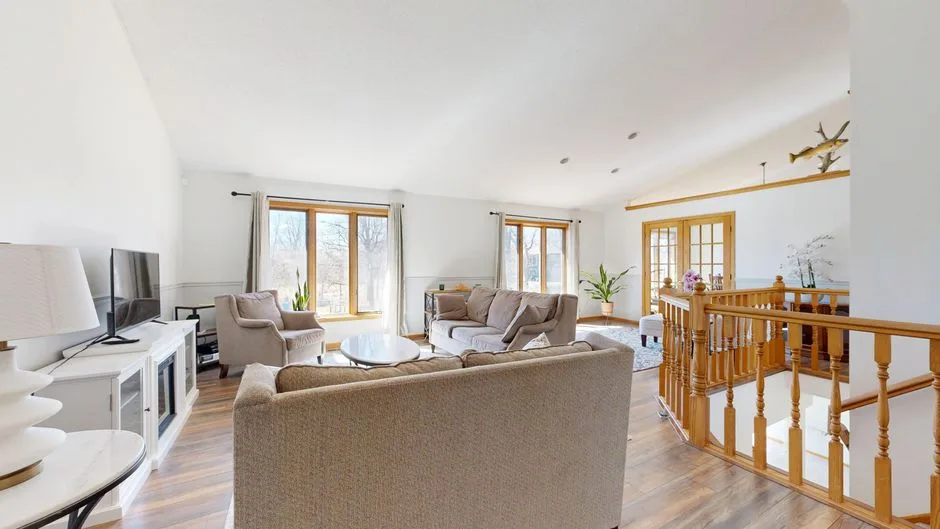Salon lumineux d’un appartement, grandes fenêtres et mobilier clair